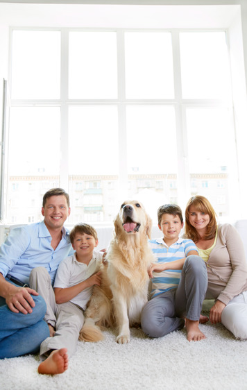 Cheerful family with their pet sitting on the floor at home